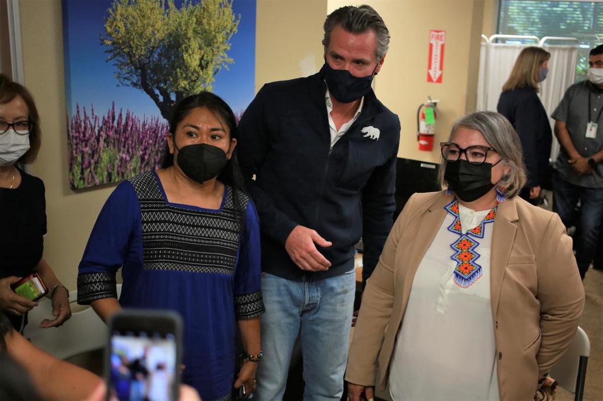 El gobernador de California, Gavin Newsom, en el centro, posó a líderes comunitarios Oralia Maceda, directora de programas del Centro Binacional para el Desarrollo Indígena Oaxaqueño (CBDIO) y Genoveva Islas, directora de Cultiva Salud y fideicomisaria de la Junta Escolar Unificada de Fresno, después de firmar el proyecto de ley que amplía la cobertura de atención médica para los residentes de California indocumentados en la Clínica Sierra Vista el martes 27 de julio de 2021 por la mañana en Fresno, CA.