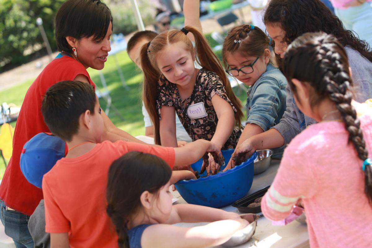 Rosalba López Ramírez, co-founder of Black Zócalo, shows children how to make seed bombs at Saturday’s Boom Oaxaca kids’ maize-planting workshop at Arte Américas.