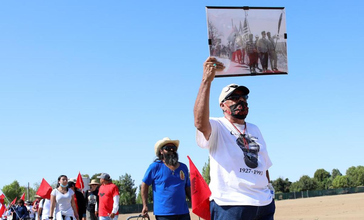 Roberto Bustos was in charge of the UFW’s historic 1966 Delano-to-Sacramento march. He sports a photo of that march while attending the start of another march at Forty Acres on Aug. 3, 2022.