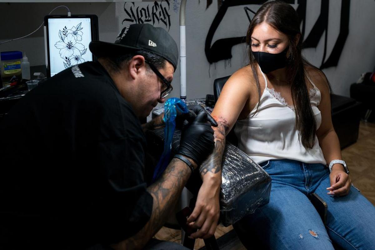 Juan Rodríguez, dueño de FTF Tattoo, mientras realiza un tatuaje en el brazo de una mujer en su local en Pacoima.