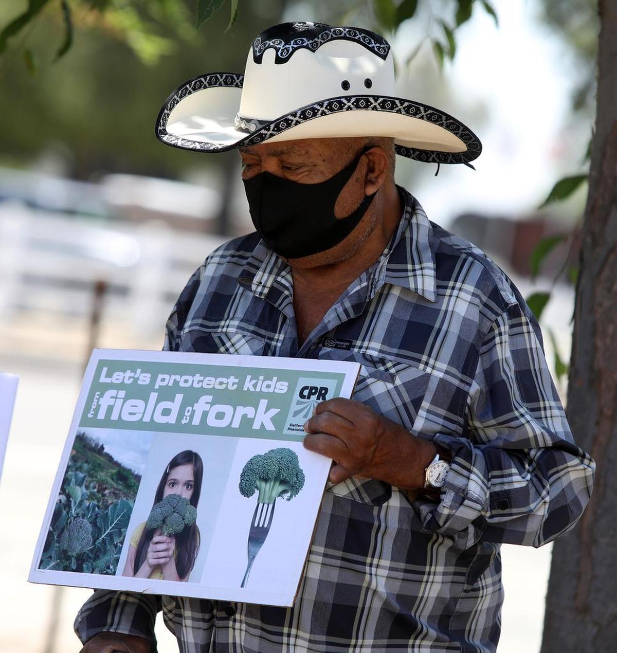 A man shows his support for an effort to get county ag commissioners to post information online about pesticide spraying in advance.
