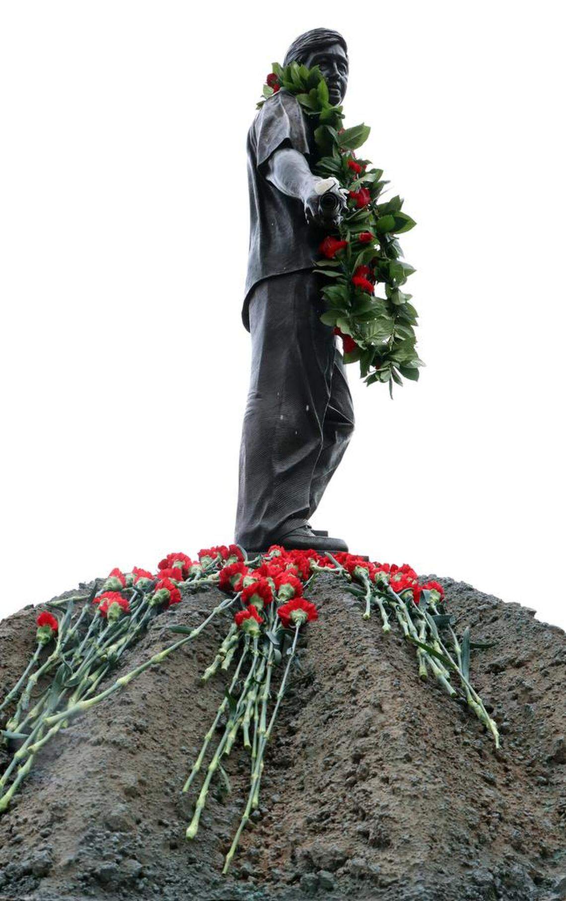 A bed of red carnations decorate the base of a bronze statute of farmworker leader César E. Chávez during March 22, 2023 celebration at Fresno State’s Peace Garden.