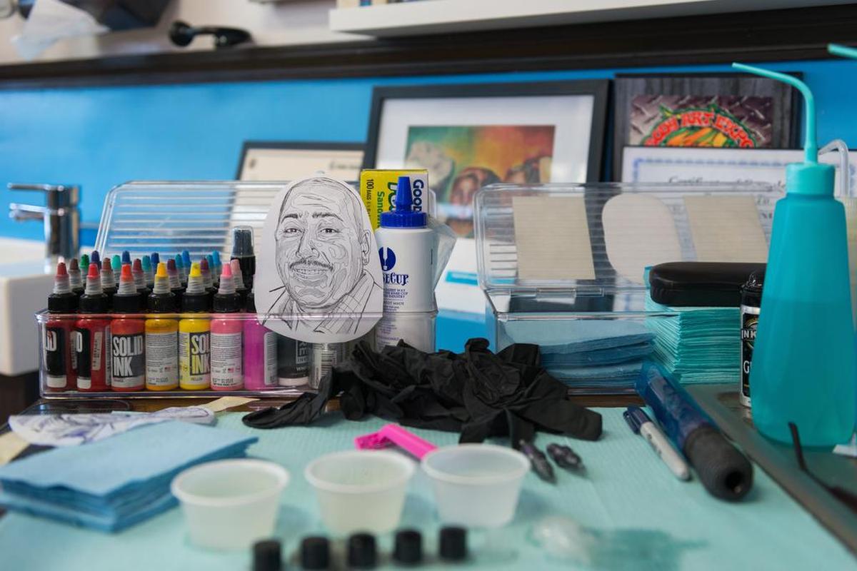 Era un sábado por la mañana en Southbay Tattoo and Body Piercing, en Carson, California, y su propietario, Efraín Espinoza Díaz Jr., se estaba preparando para el primer tatuaje del día: el retrato conmemorativo de un hombre que su viuda quería en su antebrazo.