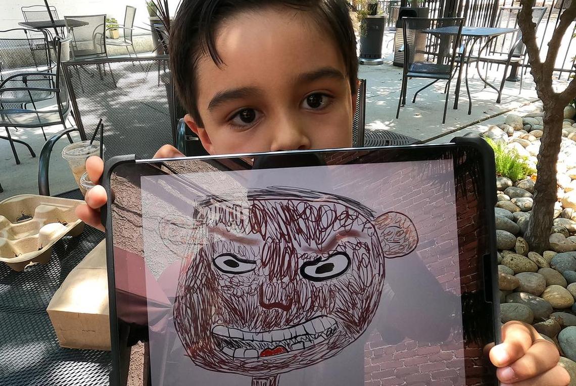 Emilio Barrera, 6, shows a self portrait he drew on a tablet. Most of his pieces are of pizza.