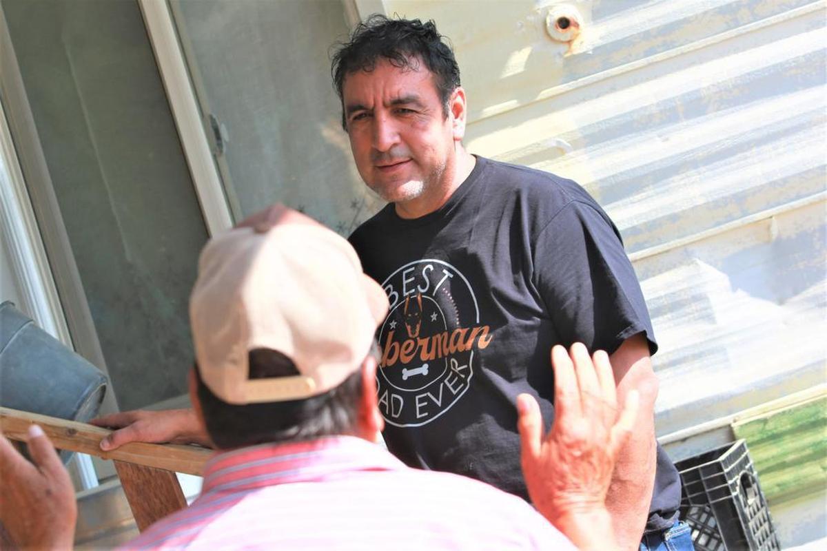 Armando Valdez escucha con atención a Salvador Aguirre a la entrada de la casa de Aguirre en Cantúa Creek.
