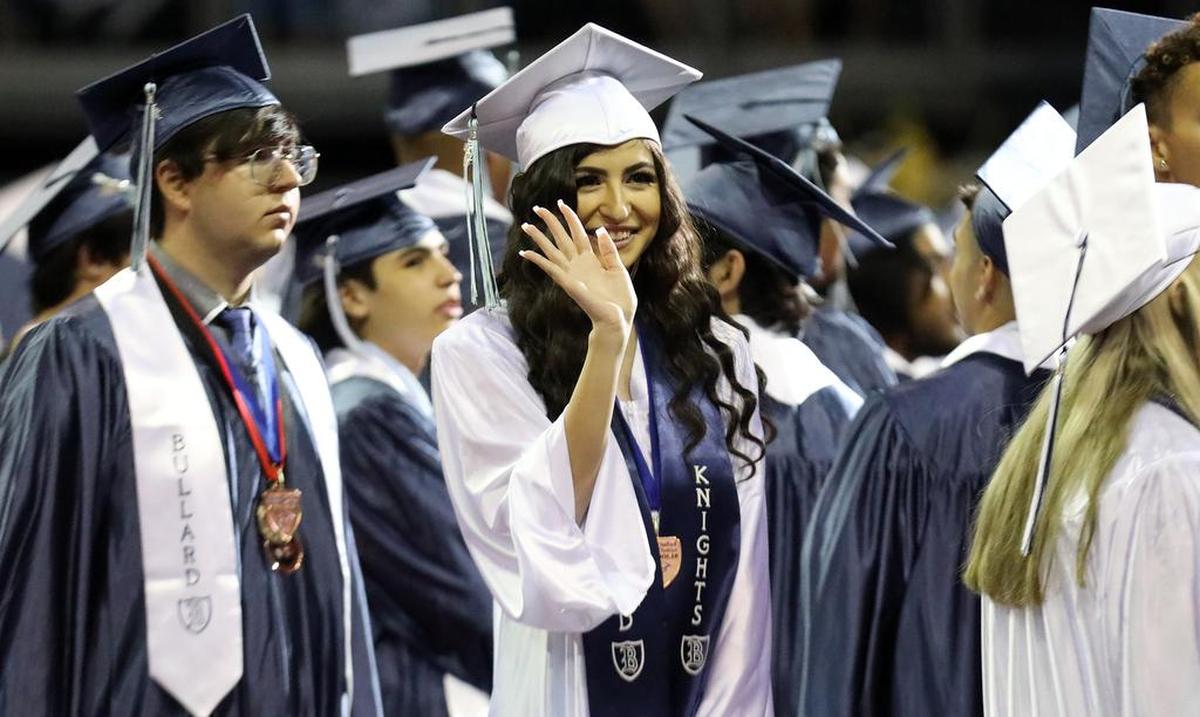 A Bullard HIgh School graduates waves to someone in the crowd at the Save Mart Center during June 8, 2022 graduation ceremony at the Save Mart Center.