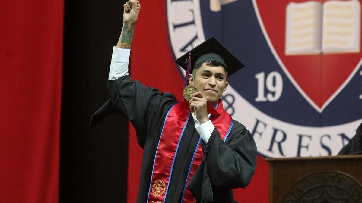 Joey Contreras, the graduate dean't medalist from the Fresno State College of Science and Mathematics, shows his medal to the audience at the Save Mart Center.