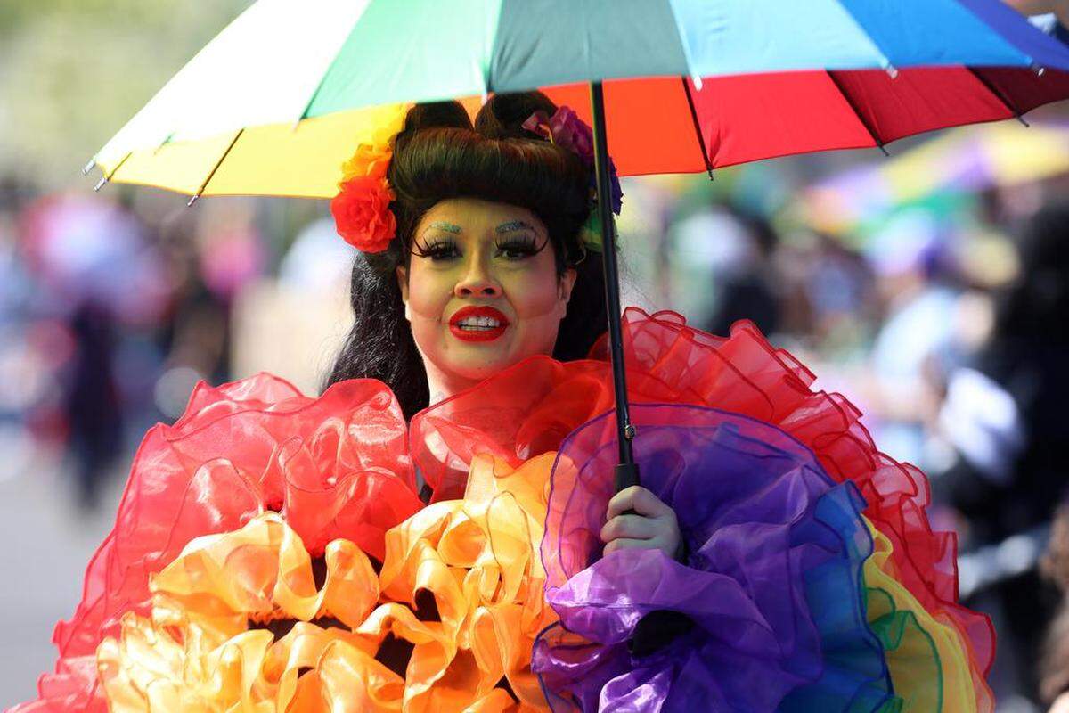 Grace Gonzales uses an umbrella to protect from the sun during the 25th annual Mardi Gras Parade in the Tower District on Feb. 19, 2023.