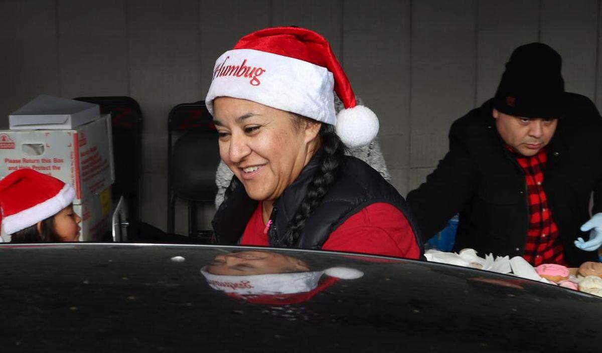 A volunteer hands out Mexican sweet bread during the 25th annual Navidad en el Barrio at the Bautista Medical Group parking lot in downtown Fresno on Dec. 17, 2022.