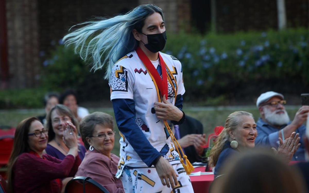 Fresno City College Fine, Performing and Communication Arts Division dean’s medallion recipient Orion Luminiferous walks up to receiving his award during the May 12, 2022 ceremony.