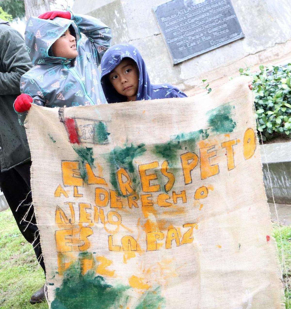 Boys hold a sign they made featuring a quote by Benito Juárez during the 217th anniversary of his birthday at Courthouse Park in Fresno on March 21, 2023.