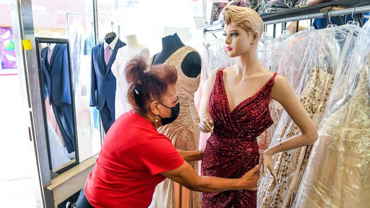 Amparo Cervantes of Barr Brothers of California bridal shop in Fresno, adjusts a mannequin while working at the shop on Tuesday, April 20, 2021.
