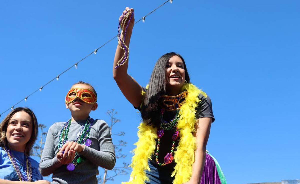 Fresno City Council Vice President Annalisa Perea dangles some beads from atop a fire truck along Olive Avenue during the 25th annual Mardi Gras Parade in the Tower District on Feb. 19, 2023.