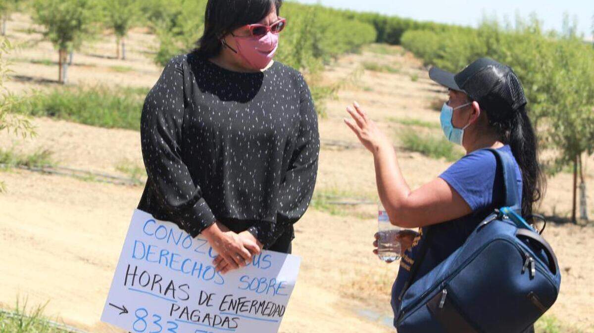La comisionada del Trabajo Lilia García-Brower habla con Oralia Maceda, directora de programas del Centro Binacional para el Desarrollo Indígena Oaxaqueño (CBDIO) en uno de los campos en el área de Goshen durante la divulgación de información a trabajadores en los campos durante la caravana móvil en el Condado de Tulare.