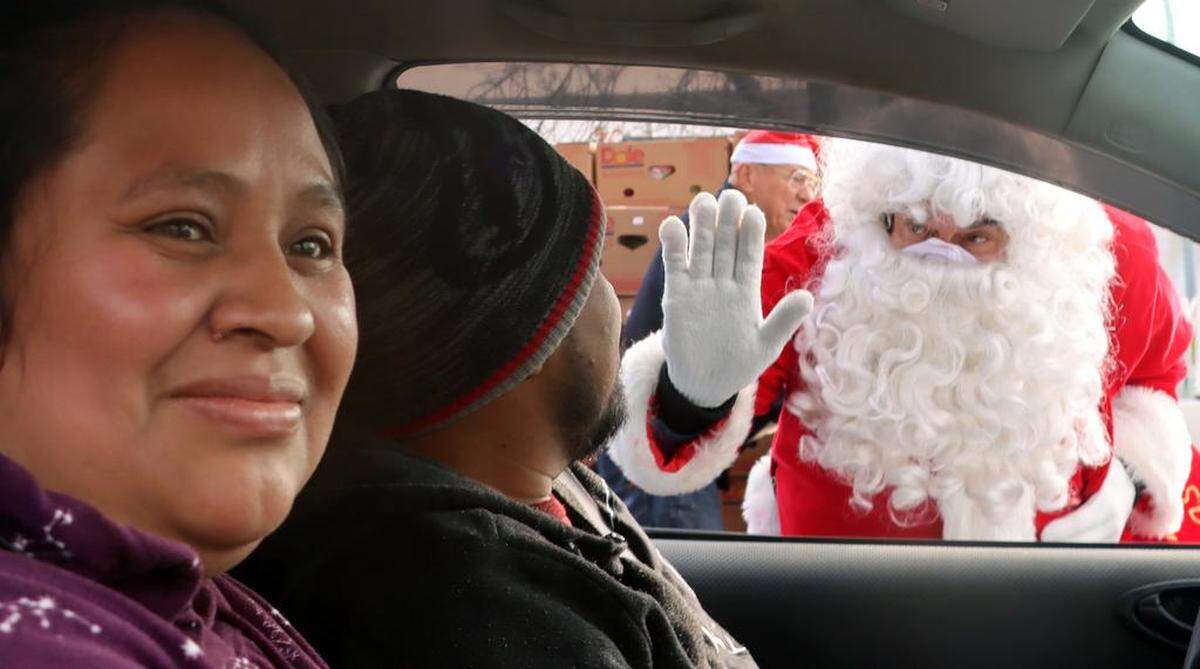 Santa Claus waves at occupants in a car at the Christmas With Lulu toy and food giveaway in Chinatown on Dec. 17, 2022. The event was sponsored by the Lulu Foundation with support from the Fresno Police Officers Association.