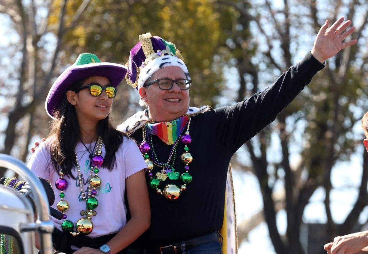 Grand Marshal Peter Robertson and Gabriela Lindo, 12, wave from atop a fire truck along Olive Avenue during the 25th annual Mardi Gras Parade in the Tower District on Feb. 19, 2023.