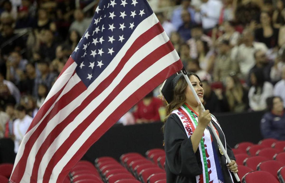 La graduada de Fresno State, Kimberly Alvarado, lleva la bandera de los EE.UU. al comienzo de la 46.a celebración de graduación chicana/latina en el Save Mart Center el 21 de mayo de 2022.