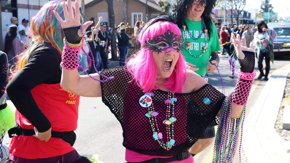 People accomanying a 1970s band get the spectators engaged along Olive Avenue during the 25th annual Mardi Gras Parade in the Tower District on Feb. 19, 2023.