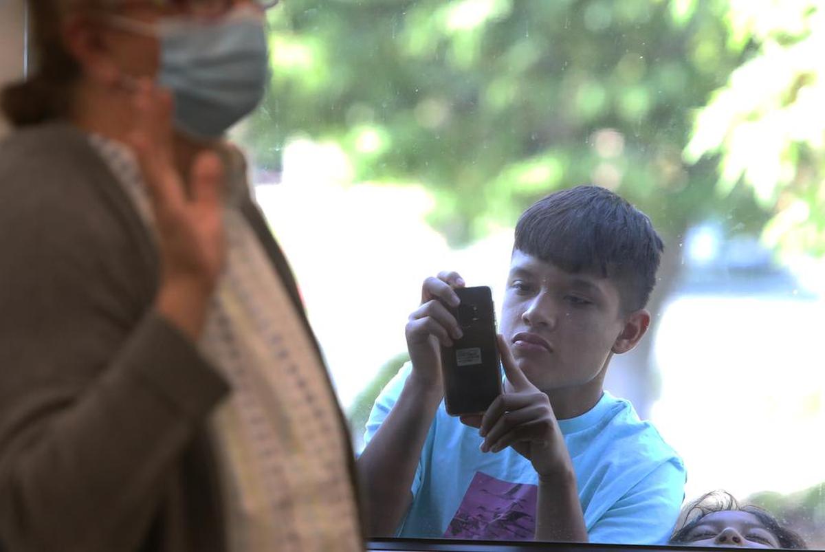 A boy takes cell photos of the July 15, 2021 naturalization ceremony from outside a window.