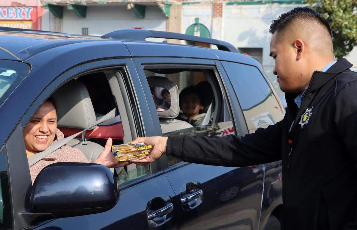 A Fresno police officer hands cookies to during the Christmas With Lulu toy and food giveaway in Chinatown on Dec. 17, 2022. The event was sponsored by the Lulu Foundation with support from the Fresno Police Officers Association.