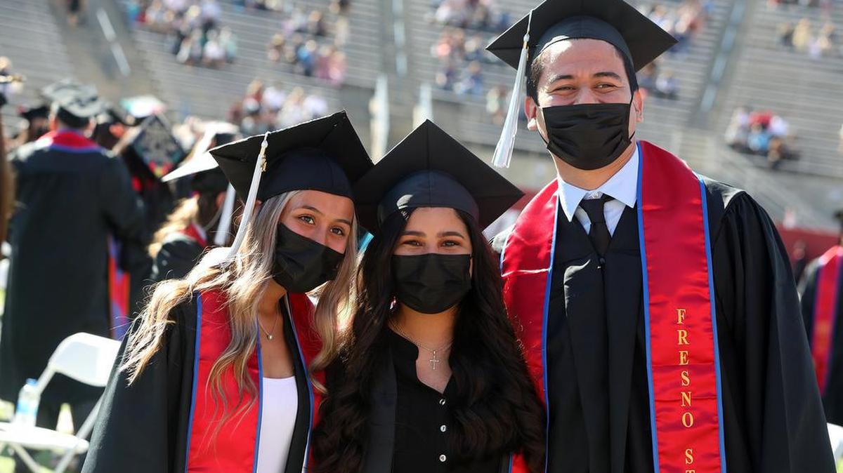 Three Fresno State graduates pose for a photo during the May 14, 2021 morning commencement at Bulldog Stadium.