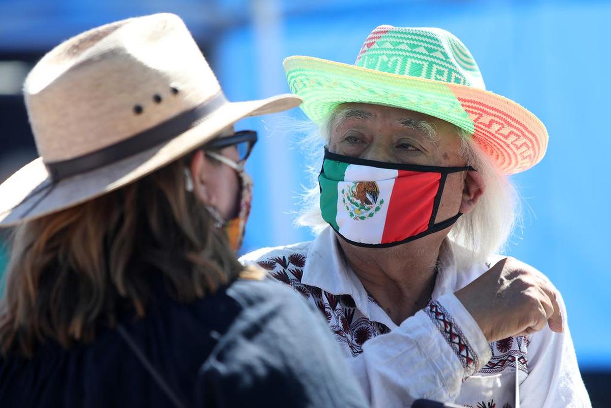 Radio Bilingüe founder/director Hugo Morales chats with Amy Kitcher of the Alliance for California Traditional Arts at the bilingual play ‘Vacúnate, Prudencio!’ during a June 13, 2021 pop up performance at the Madera fairgrounds.