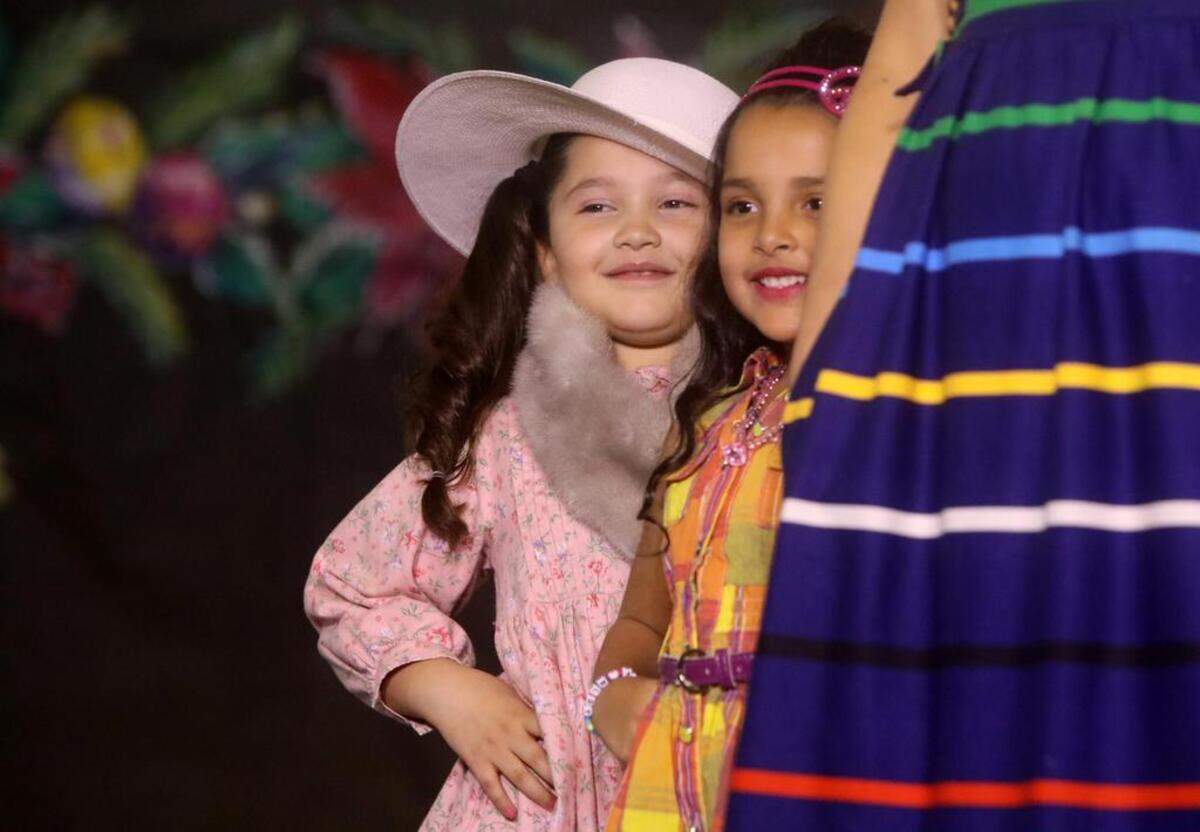 Two girls peer from behind an adult model during the 47th Fiesta Navideña Fashion Show at Fresno Fields on Dec. 4, 2022. The fundraiser was sponsored by the League of Mexican American Women.