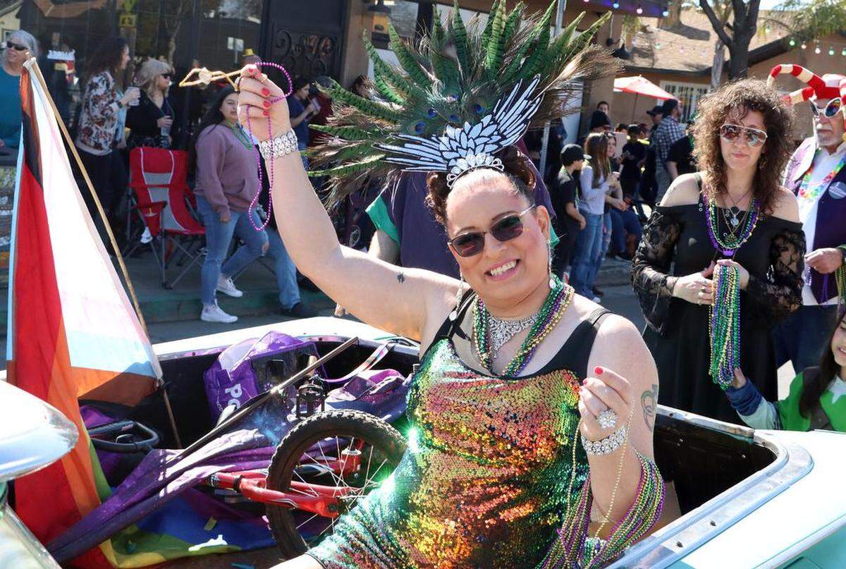 Rocío De La Rosa waves are spectators along Olive Avenue during the 25th annual Mardi Gras Parade in the Tower District on Feb. 19, 2023.