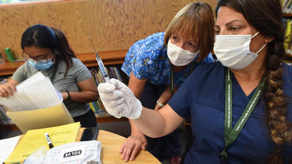 La enfermera Cynthia Norvill del Departamento de Salud del Condado Tulare, y Sheri Flores, LVN, preparan una vacuna durante una clínica en Tipton Library, el 29 de julio de 2021.