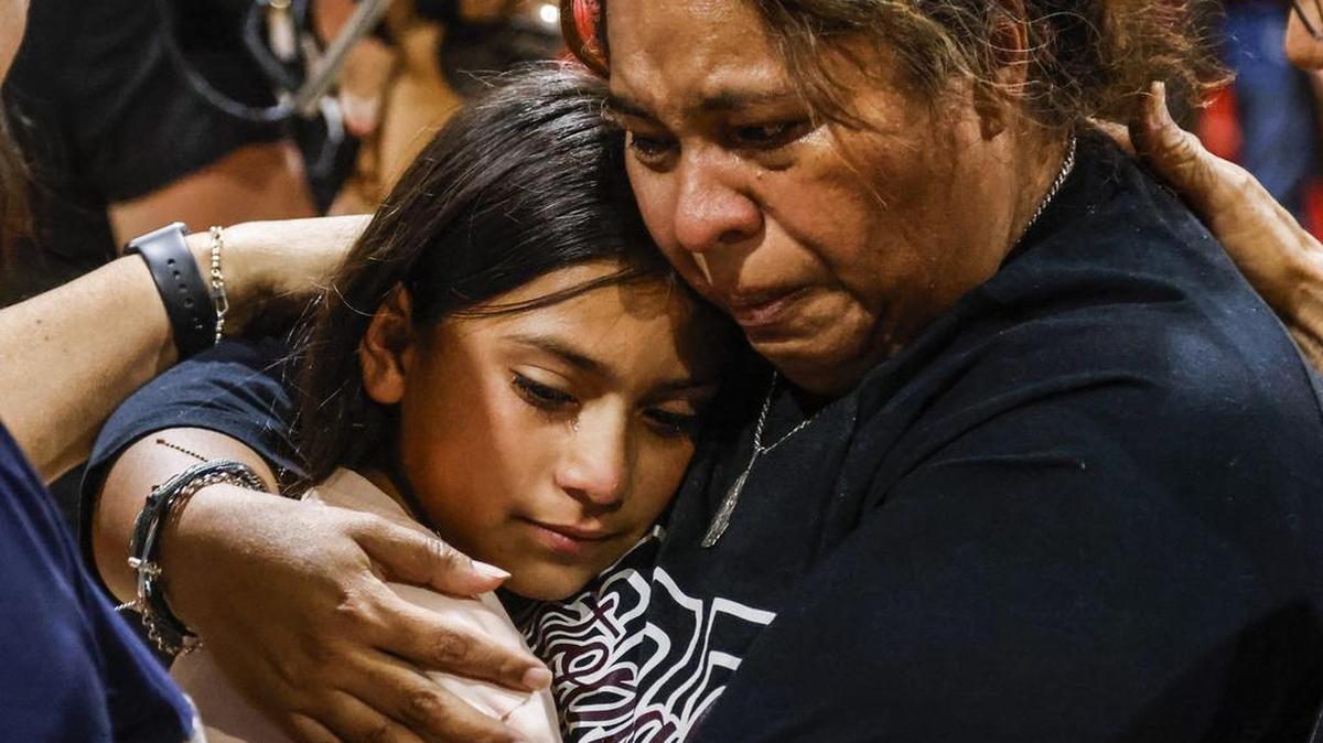 Una mujer llora mientras abraza a una niña, durante una reunión de la comunidad en el recinto ferial del condado de Uvadle, tras un tiroteo masivo en la escuela primaria Robb en Uvalde, Texas, Estados Unidos, este jueves.