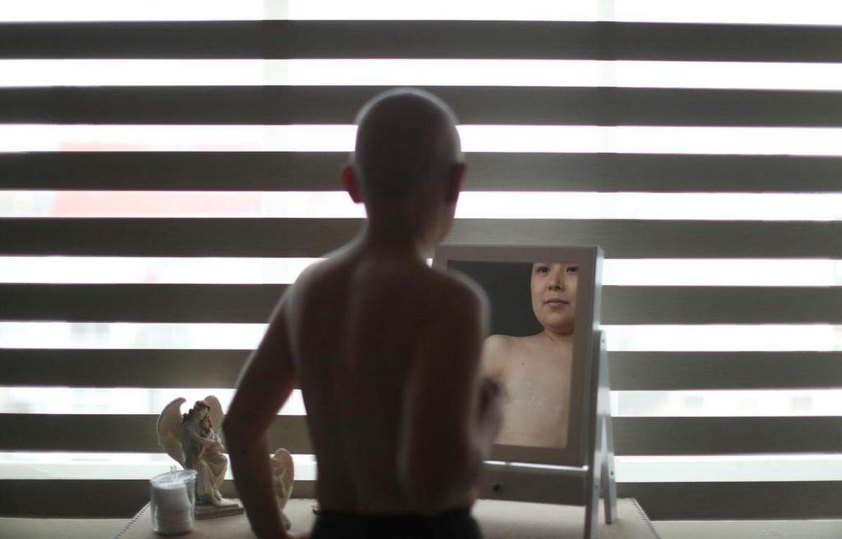 Lorena Estrada paciente con cáncer de mama se observa en un espejo el 17 de octubre de 2022 en Ciudad de México.