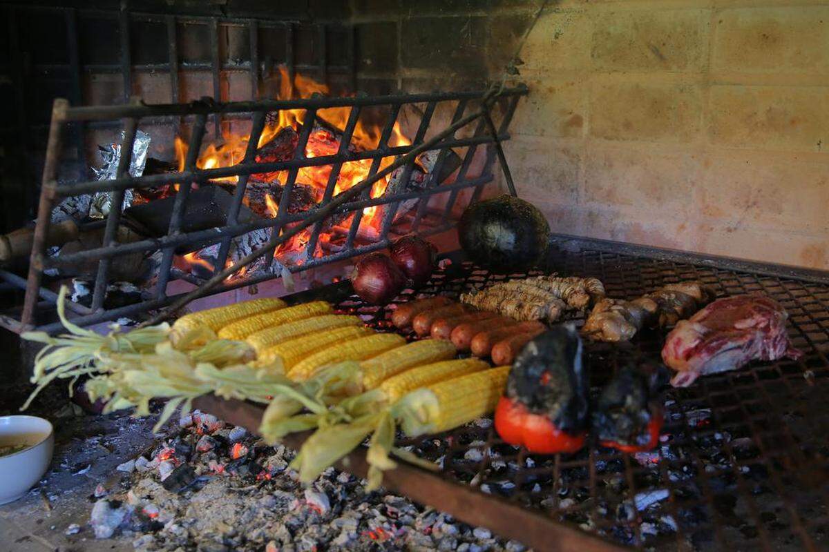 Piezas de carne y verduras se cocinan a la parrilla durante un asado en la casa del asador profesional uruguayo Sebastián Manito, el 20 de diciembre de 2022, en el departamento de Canelones, Uruguay.