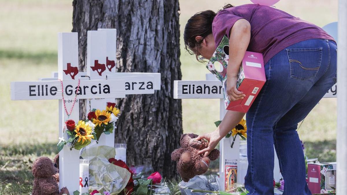 Una mujer pone un animal de peluche junto a una cruz con el nombre de una víctima después de un tiroteo masivo en la Escuela Primaria Robb en Uvalde, Texas.