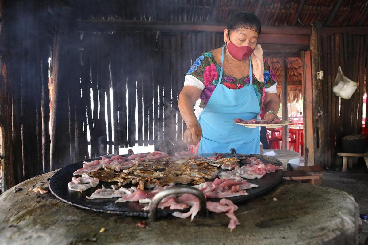 Una mujer prepara poc chuc, carne de cerdo aderezada en el restaurante La Tía de Kaua, el 23 de julio de 2022 en el poblado de Tikuch, Valladolid, estado de Yucatán.