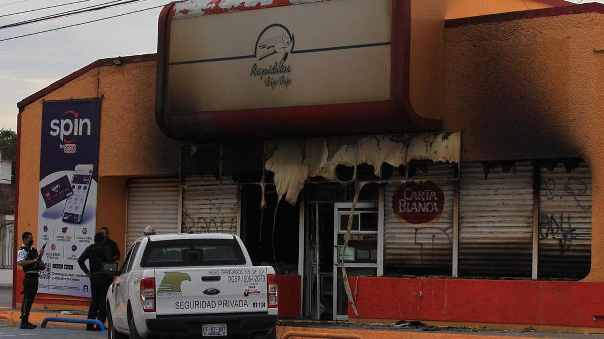 Policías Estatales y de seguridad privada vigilan una tienda que fue incendiada por personas armadas hoy en Ciudad Juárez, estado de Chihuahua.