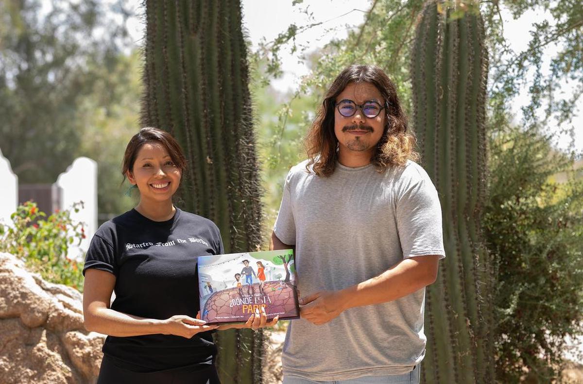 La activista Ángeles Maldonado, junto al artista Edward Dennis, mientras muestran la portada de su libro ‘¿Dónde Está Papi?’ que expone el dolor de los niños migrantes.