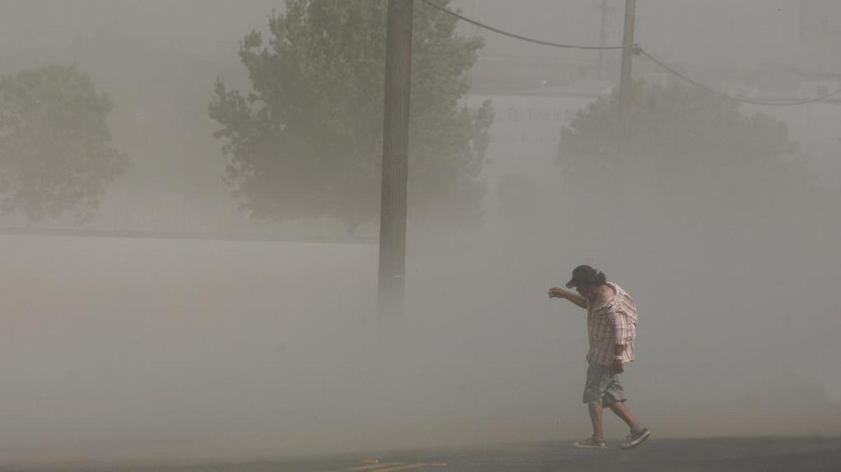 CRAIG KOHLRUSS/THE FRESNO BEE Duststorms like this one that blasted Fresno, Ca. in June can carry millions of spores from the fungus that causes Valley Fever. A man tries to navigate through heavy winds and dust blowing along G Street in downtown Fresno Monday, June 4, 2012.