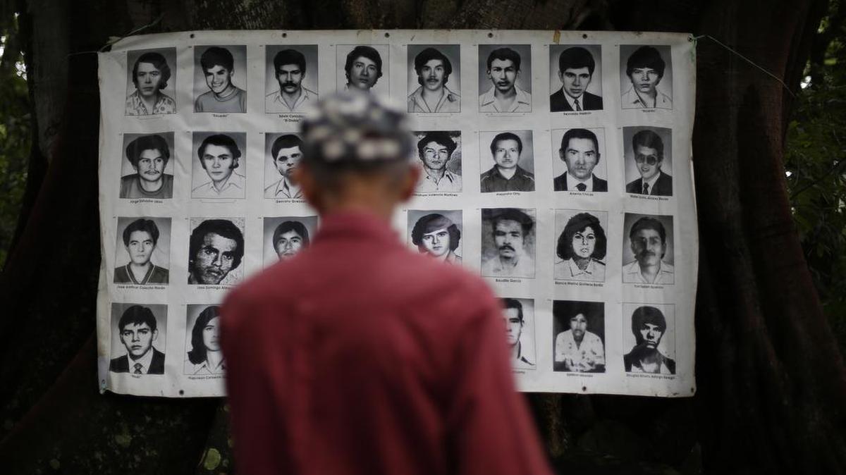 Un hombre observa fotografías de civiles asesinados durante la guerra civil salvadoreña en Nueva Trinidad.
