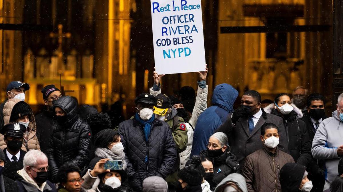 A person holds a sign following funeral services for slain New York City police officer Jason Rivera outside of St. Patrick’s Cathedral in New York.