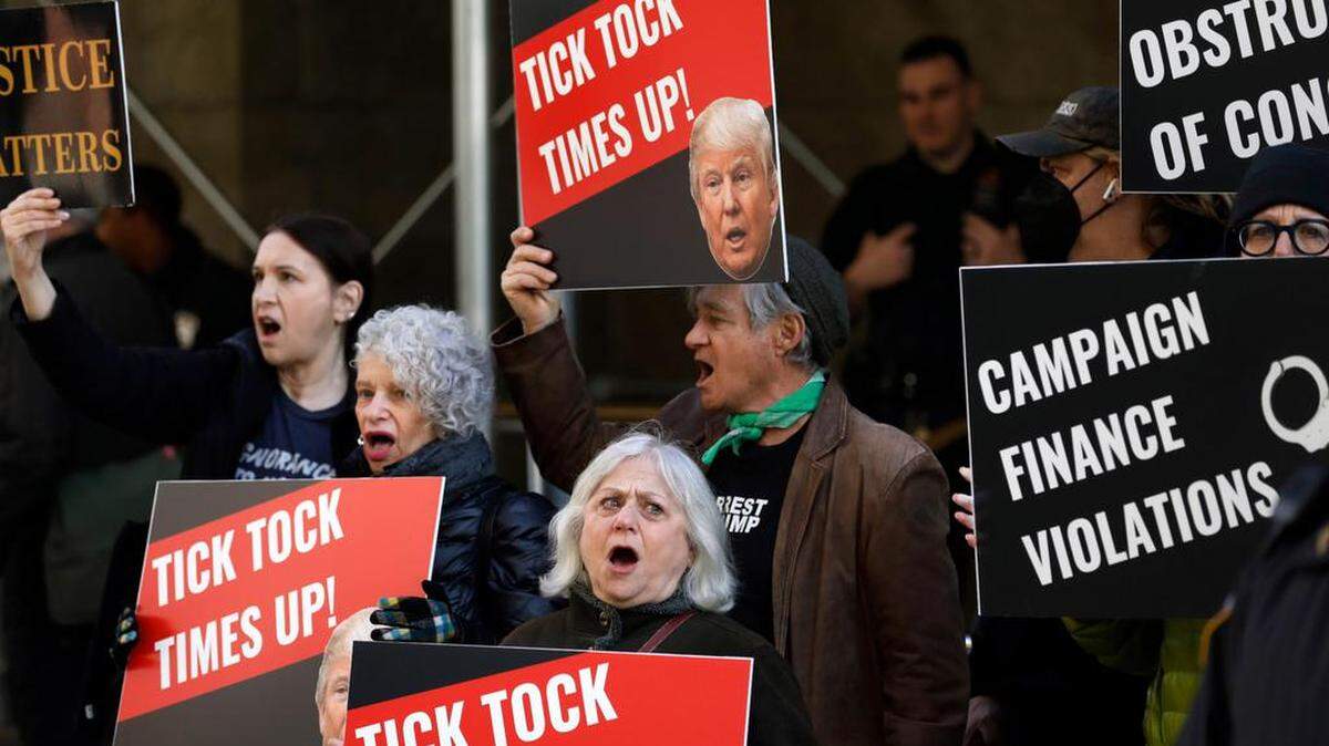 Los manifestantes gritan y sostienen carteles frente al Tribunal Penal de Nueva York antes de una posible acusación del expresidente Donald Trump en Nueva York.