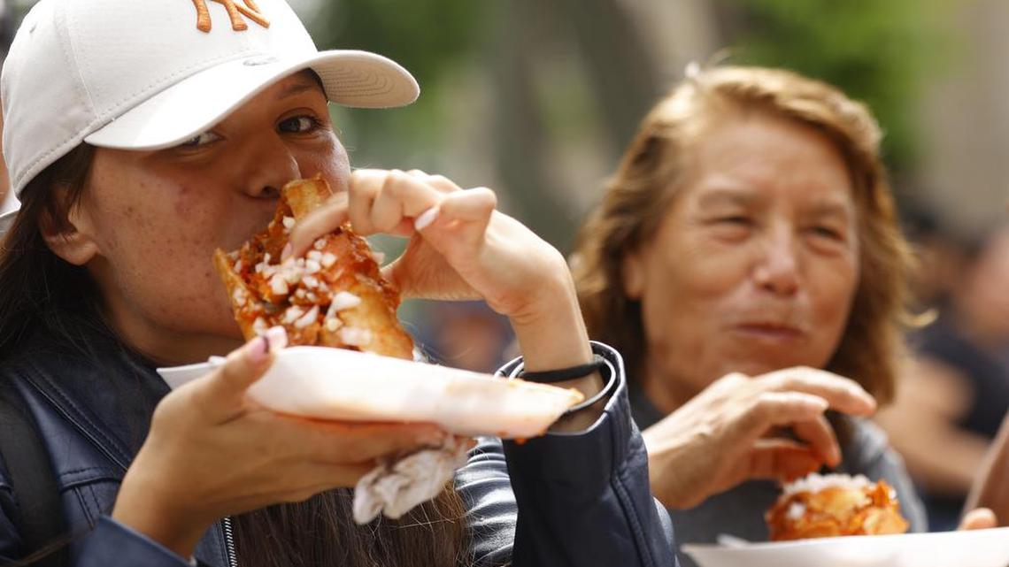 Personas comen tortas en el marco del Día de la Torta Ahogada en el centro histórico de la ciudad de Guadalajara, Jalisco.