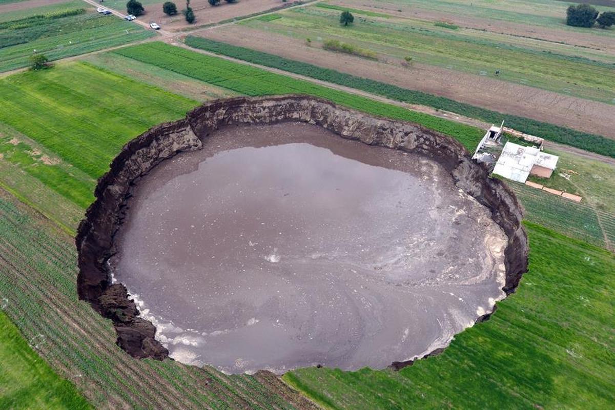The large sinkhole that appeared almost a week ago in the central Mexican state of Puebla continued to spread this Friday and caused the collapse of a wall and a bedroom of the house located on the edge of the hole. / El gran socavón aparecido hace casi una semana en el céntrico estado mexicano de Puebla siguió extendiéndose este viernes y provocó el derrumbe de una barda y de una recámara de la casa ubicada en el borde del agujero.