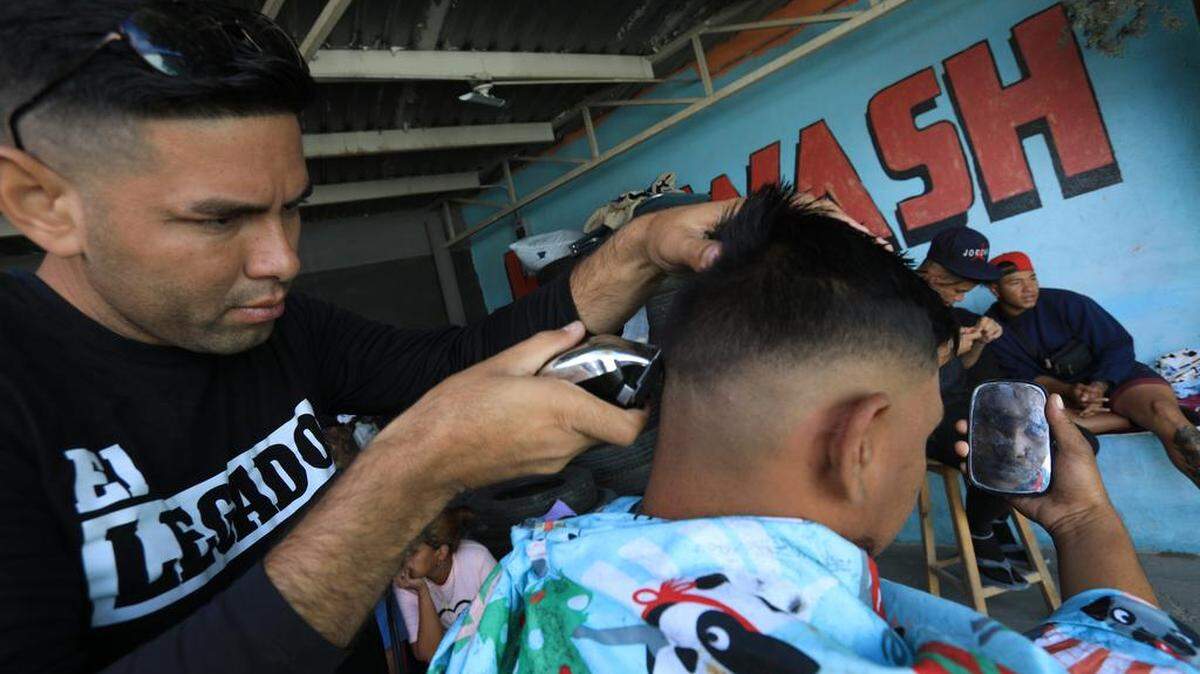 José Miguel Ceballos, a migrant from Venezuela, trims the hair of a customer in Ciudad Juárez, Chihuahua. Many Venezuelan migrants have turned to barbering to make some money.