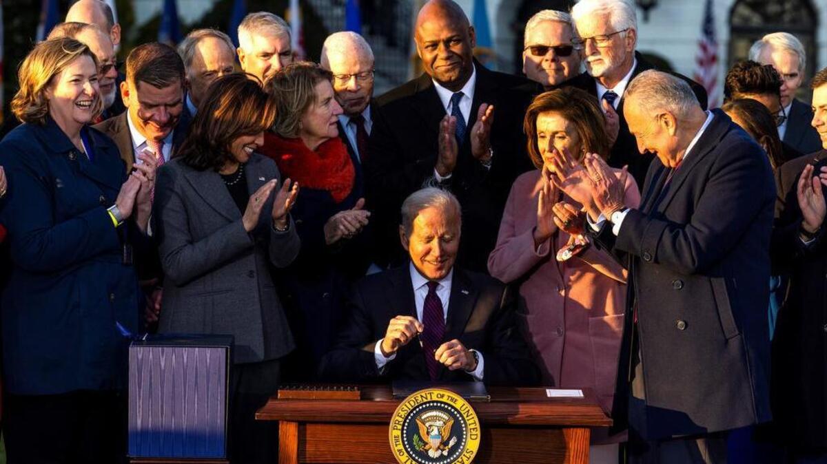 President Joe Biden, surrounded by lawmakers, signs the bipartisan Infrastructure Investment and Jobs Act on the South Lawn of the White House in Washington, D.C.