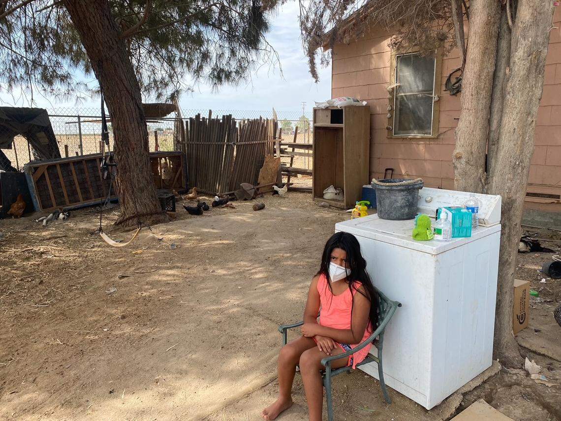 Kenia García, de 10 años, se sienta frente a la casa de su familia en Raisin City. Su hermana mayor dio positivo por COVID-19 a fines de agosto.