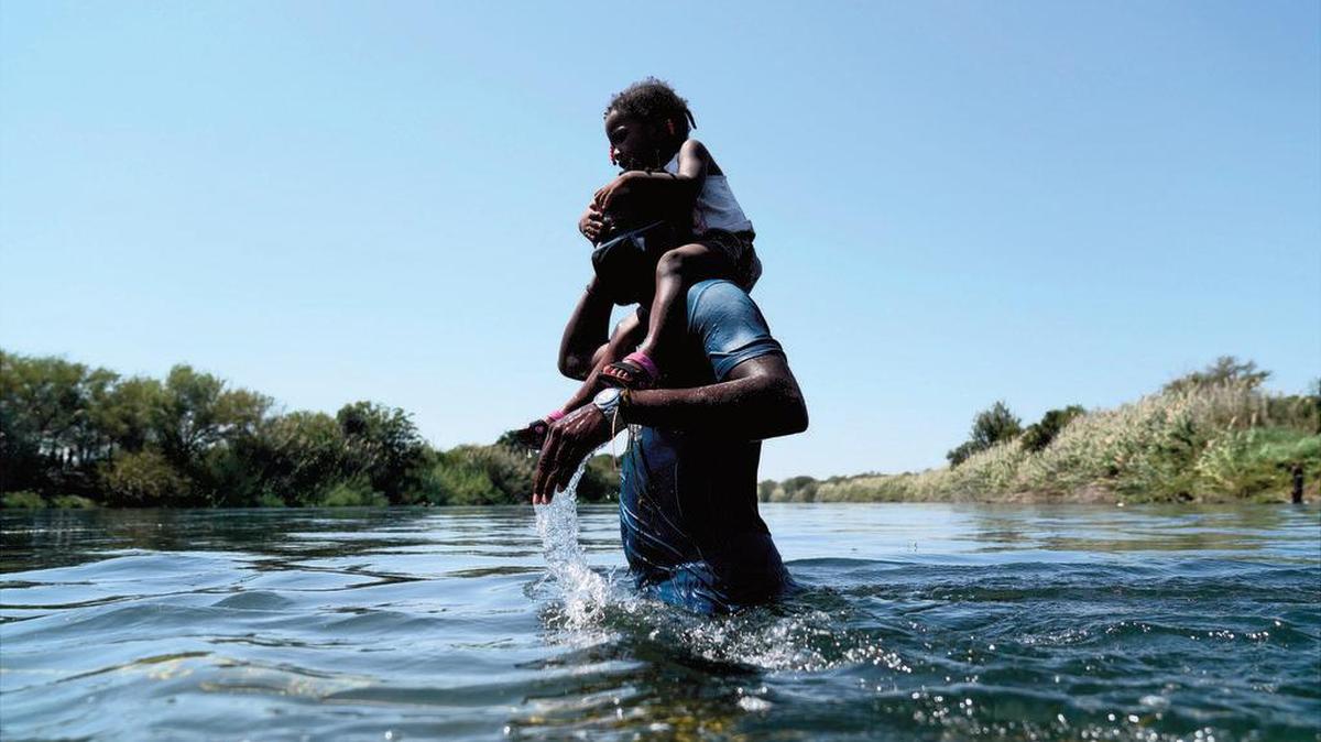 A man carrying a child on his shoulders wades across the Río Grande from the United States to México last week.